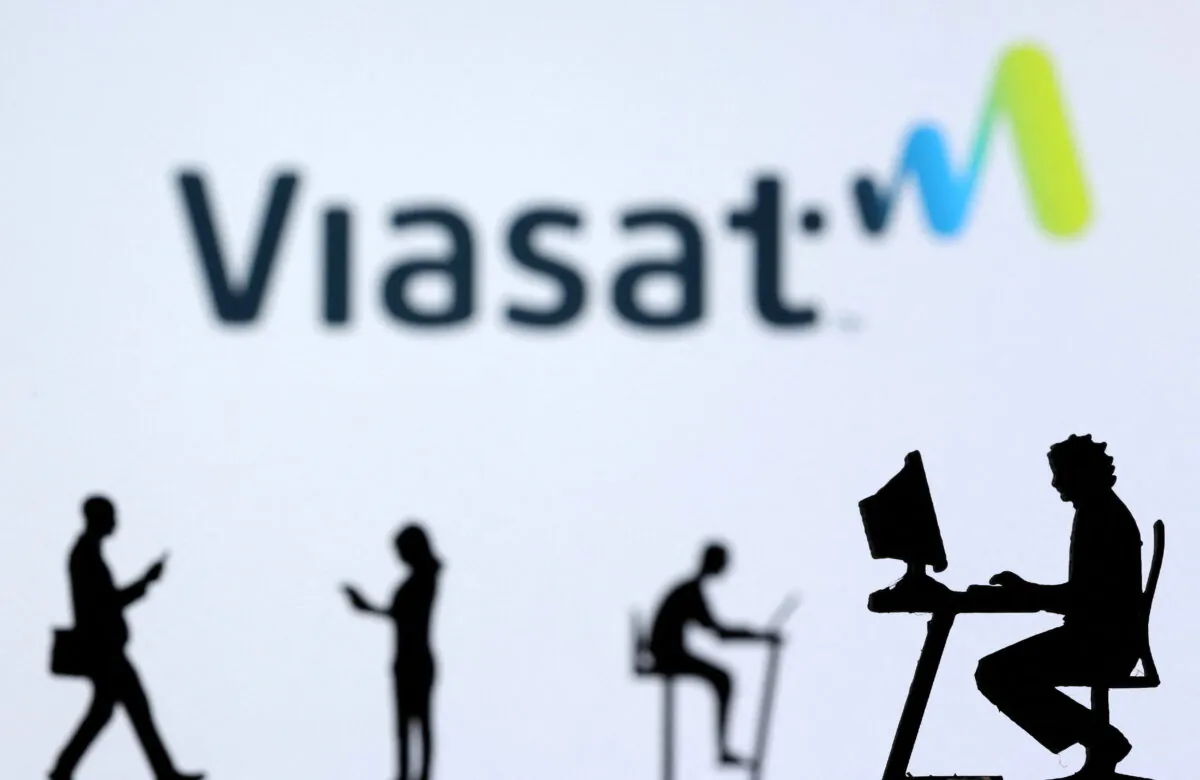 Small toy figures with laptops and smartphones are seen in front of displayed Viasat Internet logo shows in this illustration, on Dec. 5, 2021. (Dado Ruvic/Illustration/Reuters)