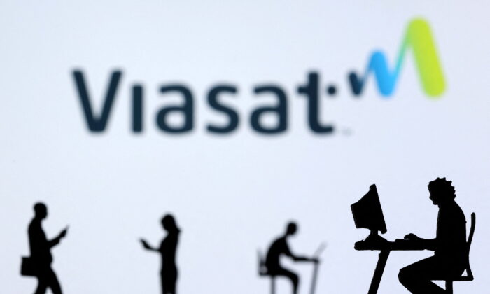 Small toy figures with laptops and smartphones are seen in front of displayed Viasat Internet logo shows in this illustration, on Dec. 5, 2021. (Dado Ruvic/Illustration/Reuters)