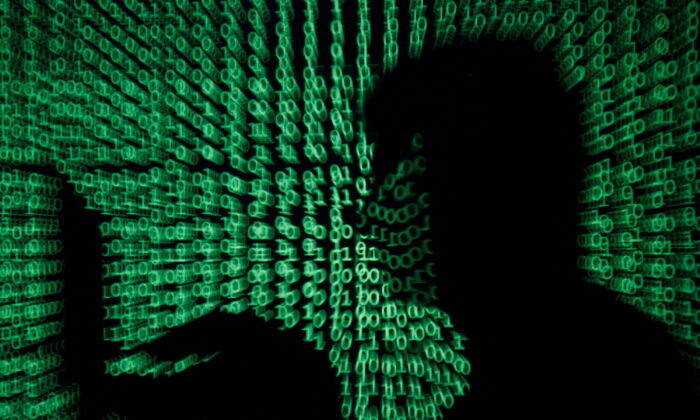 A man holds a laptop computer as cyber code is projected on him in this illustration picture taken on May 13, 2017. (Kacper Pempel/Illustration/Reuters)