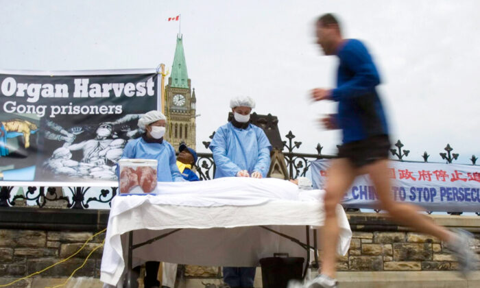 A man jogs past Falun Gong practitioners using a mock organ harvesting display to raise awareness about the Chinese Communist Party's billion-dollar, state-sanctioned murder-for-organs industry, on Parliament Hill in Ottawa on May 2, 2008. (The Canadian Press/Tom Hanson)