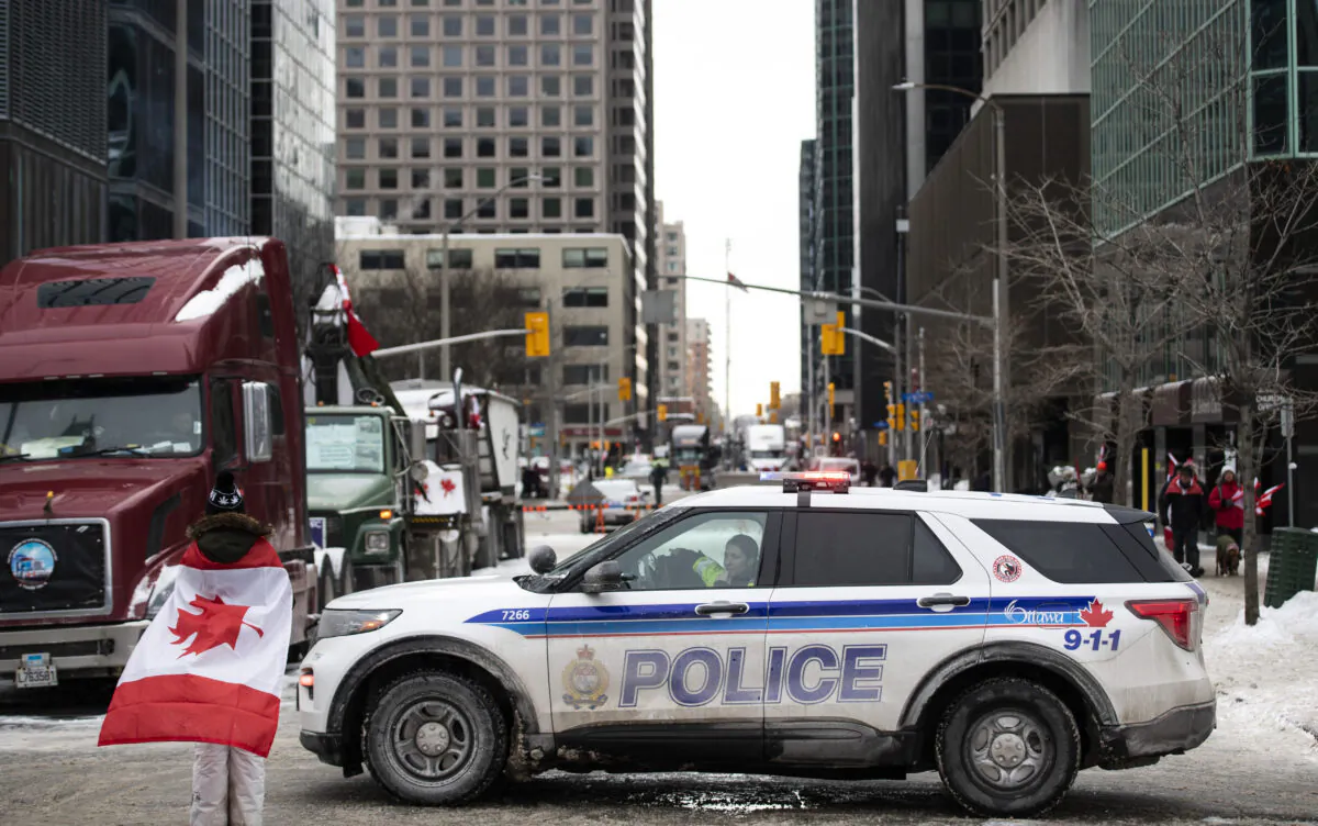 An Ottawa Police vehicle blocks off Kent Street in front of parked trucks as a protest against COVID-19 restrictions that has been marked by gridlock and the sound of truck horns continues into its second week, in Ottawa, on Sunday, Feb. 6, 2022. THE CANADIAN PRESS/Justin Tang