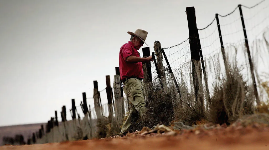 David Coverdale from the Dog Fence Board repairs a section of the Dog Fence near Marree, South Australia on June 10, 2005. (Photo by Ian Waldie/Getty Images)