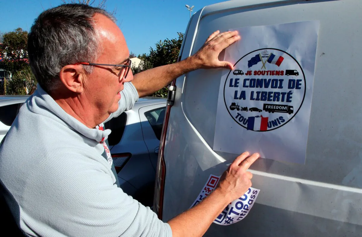 A man puts a poster that reads "Liberty Convoy" on a van before leaving for Paris, in Bayonne, southwestern France, on Feb. 9, 2022. (Bob Edme/AP Photo)