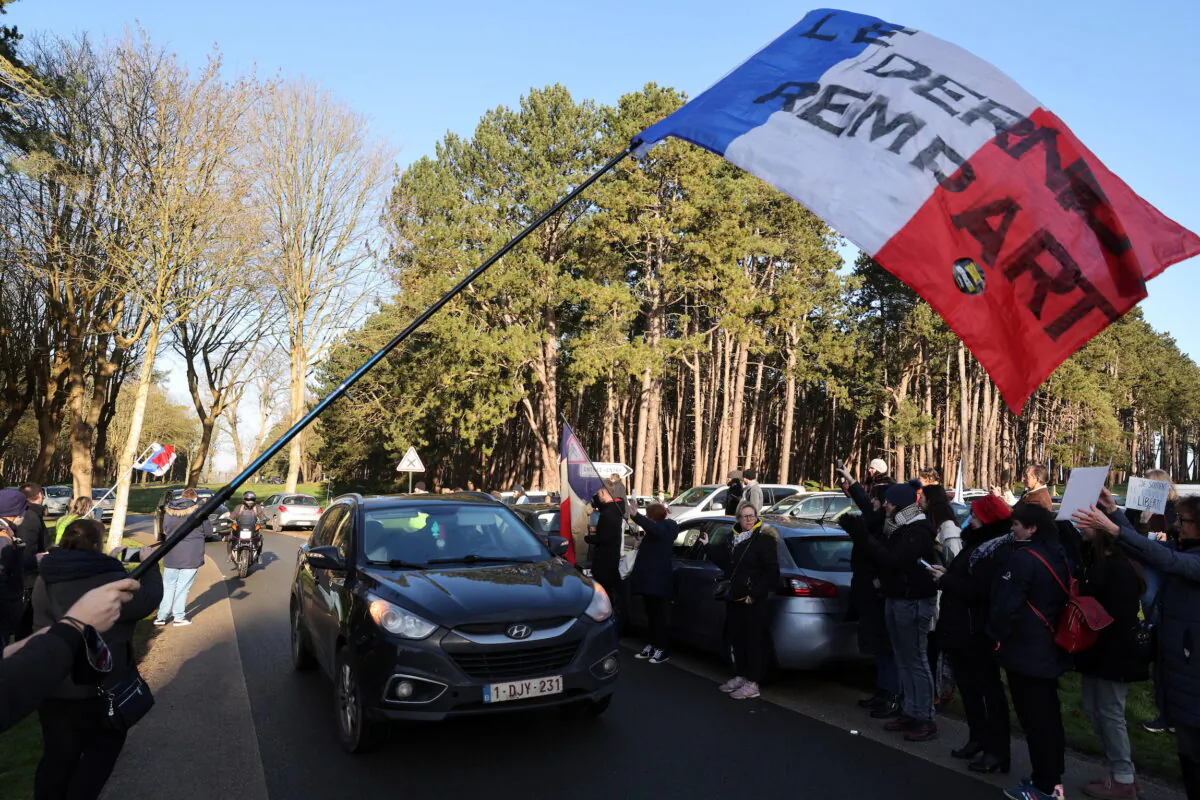 Supporters wave the French national flag and cheer French anti-COVID restrictions car drivers near the Canadian National Memorial in Vimy, northern France, on Feb. 11, 2022. The slogan reads "The last bastion." (Pascal Rossignol/Reuters)