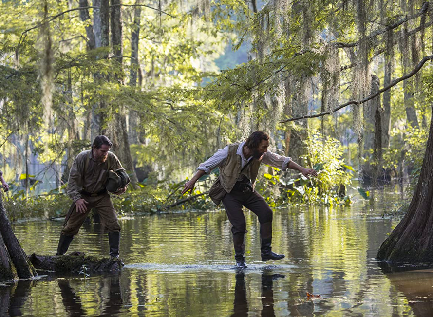two men cross a swamp in Free State of Jones