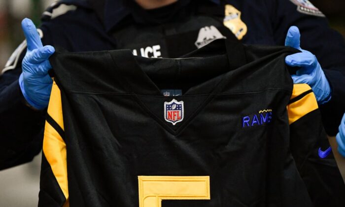 A person holds a fake NFL jersey as officers with US Customs and Border Protection (CBP) demonstrate the inspection of a shipment for illegal and counterfeit NFL items during a press conference ahead of the Super Bowl at the Air Freight Federal Inspection Facility near Los Angeles International Airport (LAX) in Los Angeles, Calif., on Feb. 4, 2022. (Patrick T. FALLON/AFP)