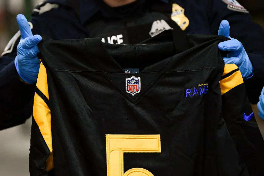 A person holds a fake NFL jersey as officers with US Customs and Border Protection (CBP) demonstrate the inspection of a shipment for illegal and counterfeit NFL items during a press conference ahead of the Super Bowl at the Air Freight Federal Inspection Facility near Los Angeles International Airport (LAX) in Los Angeles, Calif., on Feb. 4, 2022. (Patrick T. FALLON/AFP)