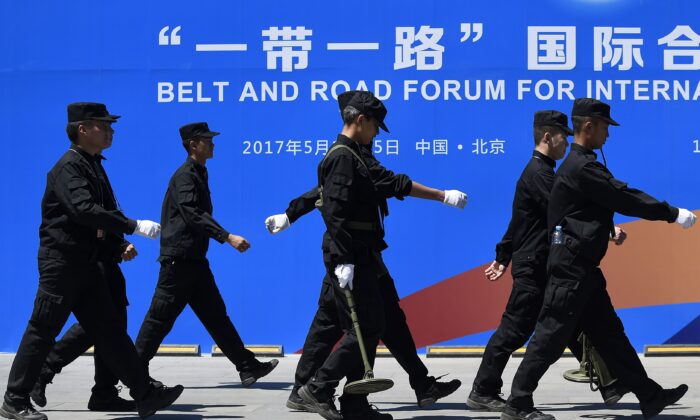 Security guards walk past a billboard for the Belt and Road Forum for International Cooperation at the forum's venue in Beijing on May 13, 2017. (Wang Zhao/AFP via Getty Images)
