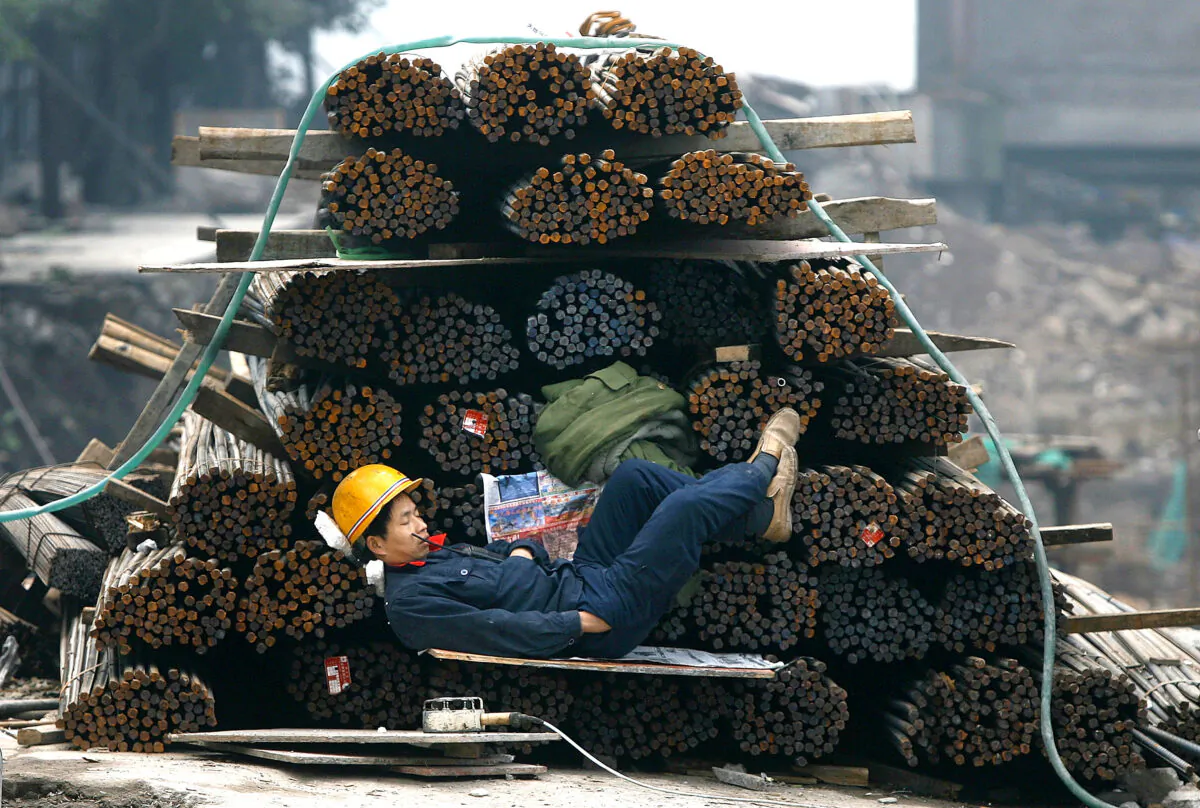 A worker sleeps in front of rolled steel at a construction site in Chongqing Municipality, China, on Jan. 26, 2007. (China Photos/Getty Images)