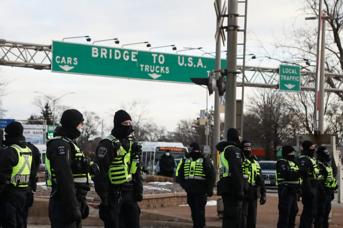 Police officers stand guard on a street as truckers and supporters block access to the Ambassador Bridge, which connects Detroit and Windsor, in protest against COVID-19 mandates and restrictions, in Windsor, Ont., on Feb. 12, 2022. (Carlos Osorio/Reuters)