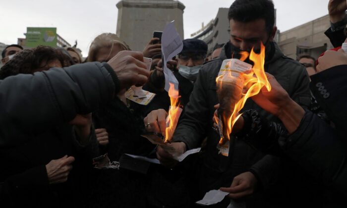 Members of Turkey's main opposition Republican People's Party burn invoices to protest high electricity prices as they gather in front of a monument of the founder of modern Turkey, Mustafa Kemal Ataturk, in Ankara, Turkey, on Feb. 9, 2022. (Burhan Ozbilici/AP Photo)