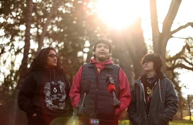 Bear Henry is joined by friends Nakita Sekhon, left, and Shae Perkins during a press conference at Beacon Hill Park in Victoria, Feb. 11, 2022. (The Canadian Press/Chad Hipolito)