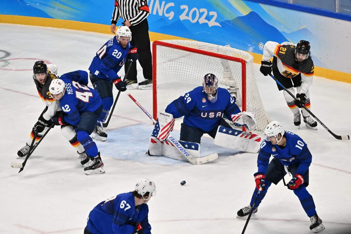 (Clockwise from L) Germany's Tom Kuehnhackl, USA's Aaron Ness, USA's Steven Kampfer, USA's goaltender Drew Commesso, Germany's Nicolas Kraemmer, USA's Matty Beniers and USA's Matt Knies eye the puck during the men's preliminary round group A match of the Beijing 2022 Winter Olympic Games ice hockey competition between USA and Germany, at the Wukesong Sports Centre, in Beijing, on February 13, 2022. (Anthony Wallace/AFP via Getty Images)