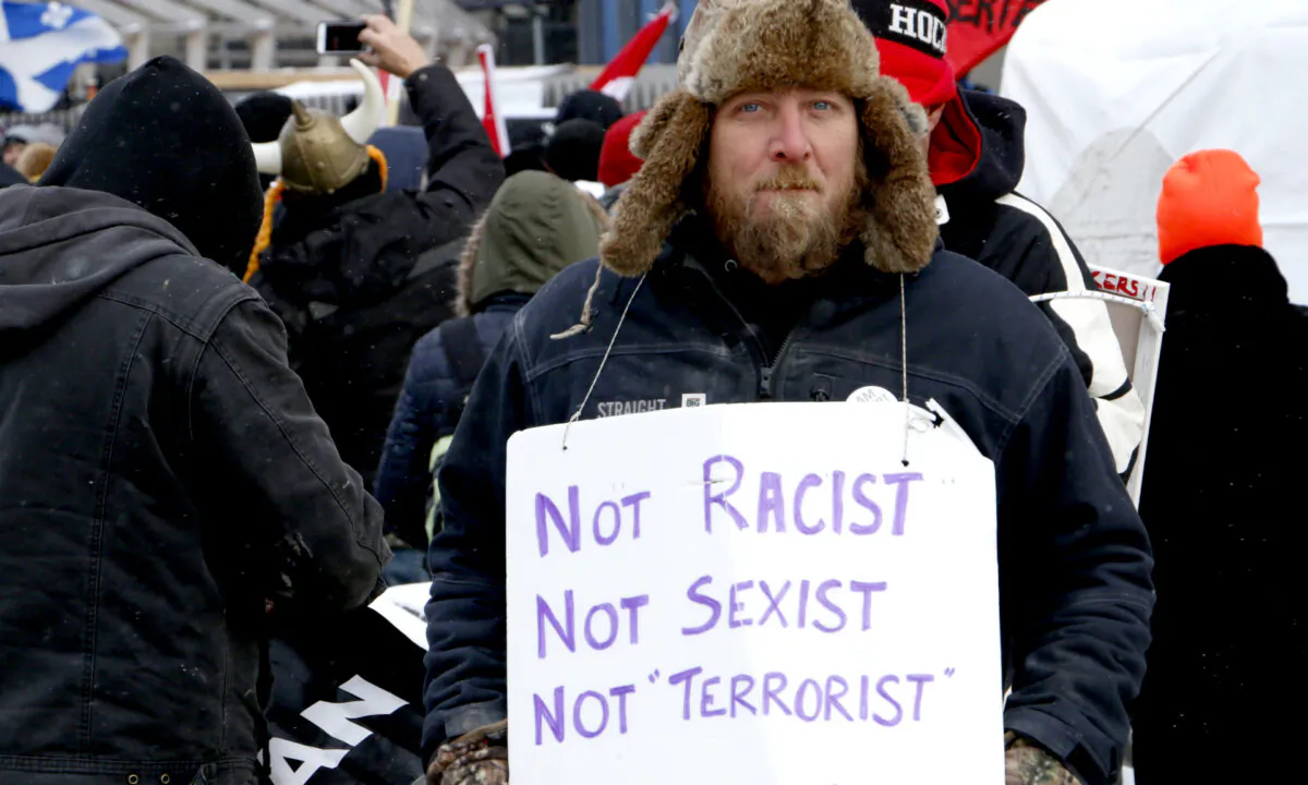 A protester holds a sign on Wellington St. in Ottawa on Feb. 12, 2022. (Noé Chartier/The Epoch Times)