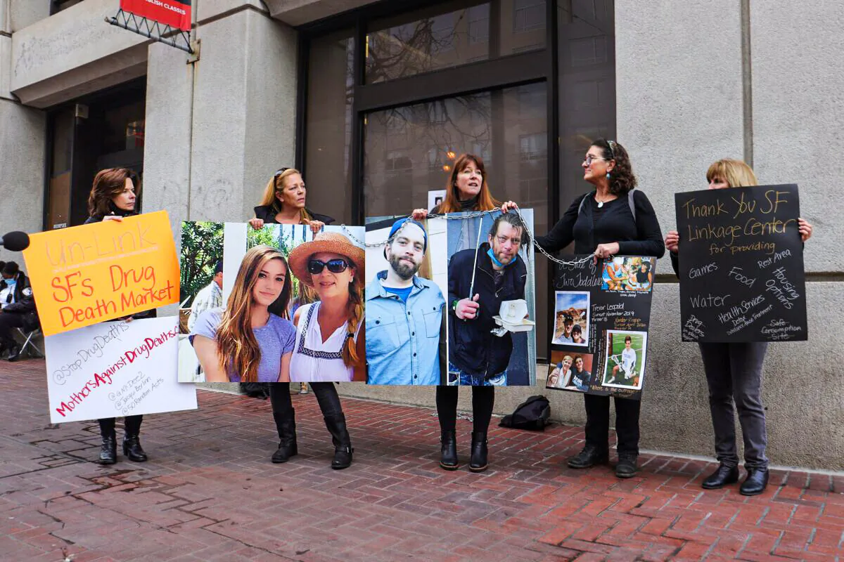 Mothers Against Drug Deaths hold a chain and posters in front of the Tenderloin Linkage Center in San Francisco on Feb. 5, 2022. (Cynthia Cai/The Epoch Times)