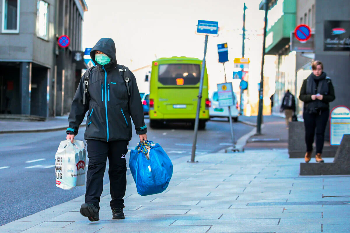 A man wearing a mask carries shopping bags as he walks on the streets of Oslo following an outbreak of COVID-19 in Oslo, Norway, on March 13, 2020. (NTB Scanpix/Hakon Mosvold Larsen via Reuters)