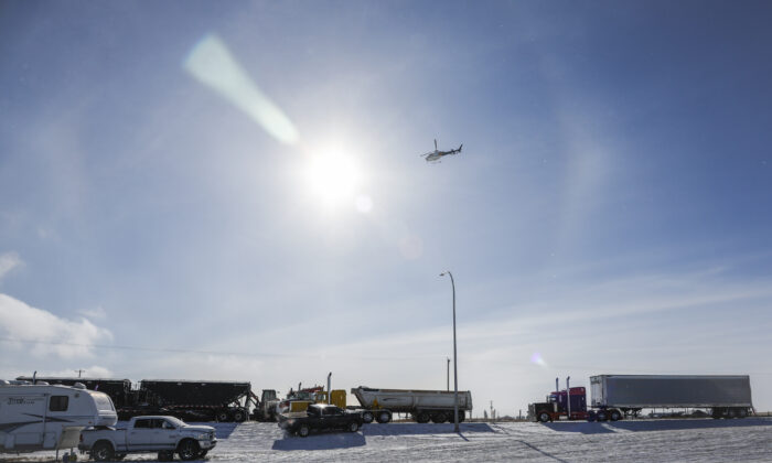 An RCMP helicopter flies over as a truck convoy demonstrating against COVID-19 mandates continues to block the highway at the U.S. border crossing in Coutts, Alta., on Feb. 2, 2022. (The Canadian Press/Jeff McIntosh)