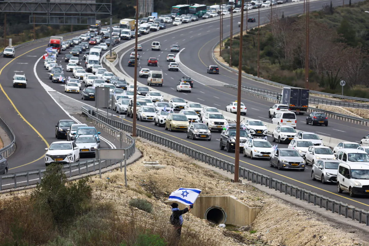 A demonstrator waves an Israeli flag as a "Freedom Convoy" inspired by Canadian truckers heads towards Jerusalem to protest against COVID-19 restrictions on Feb. 14, 2022. (Ronen Zvulun/Reuters)