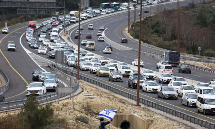 A demonstrator waves an Israeli flag as a "Freedom Convoy" inspired by Canadian truckers heads towards Jerusalem to protest against COVID-19 restrictions on Feb. 14, 2022. (Ronen Zvulun/Reuters)