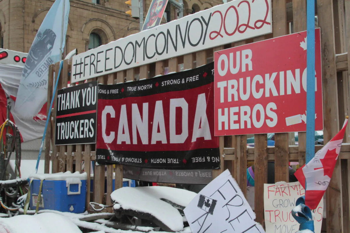 Signs supporting the Freedom Convoy 2022 adorn fences along Wellington St. in downtown Ottawa on Feb. 12. (Richard Moore/The Epoch Times)