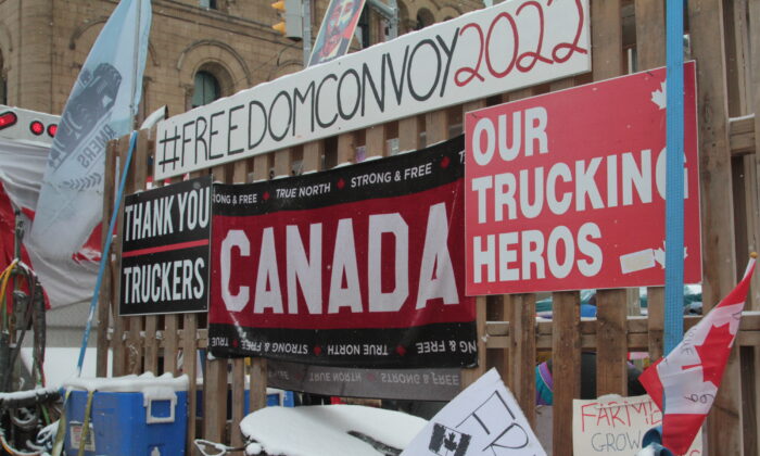 Signs supporting the Freedom Convoy 2022 adorn fences along Wellington St. in downtown Ottawa on Feb. 12. (Richard Moore/The Epoch Times)