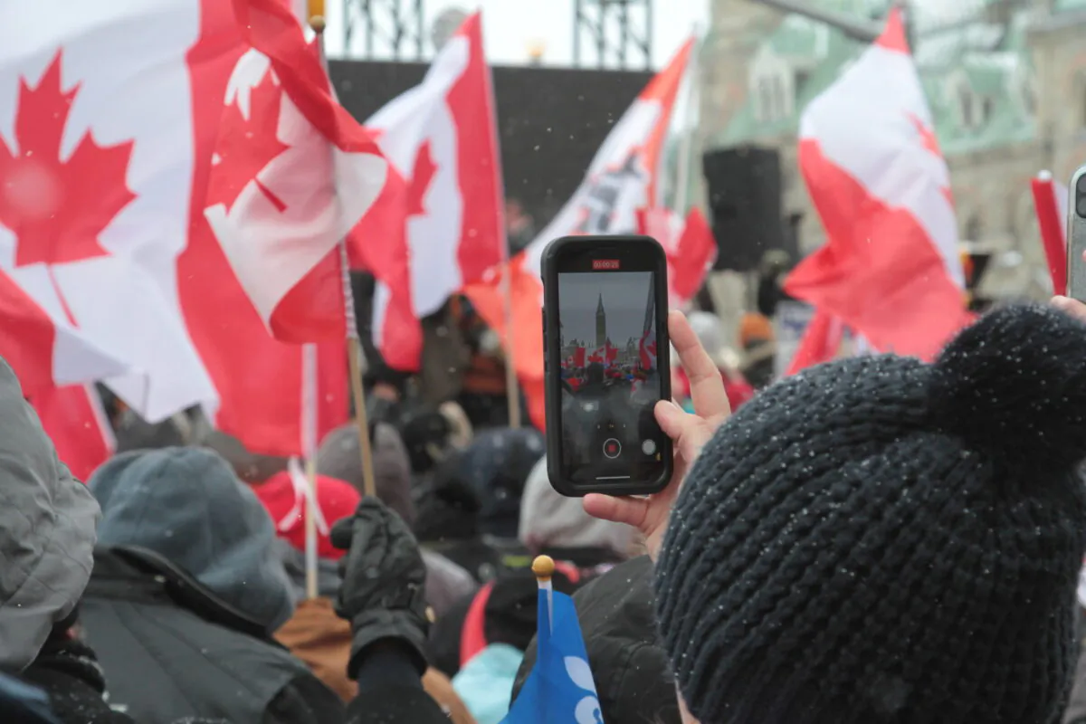 A protester takes a photo of the crowd at a rally on Feb. 12, 2022, in central Ottawa. (Richard Moore/The Epoch Times)