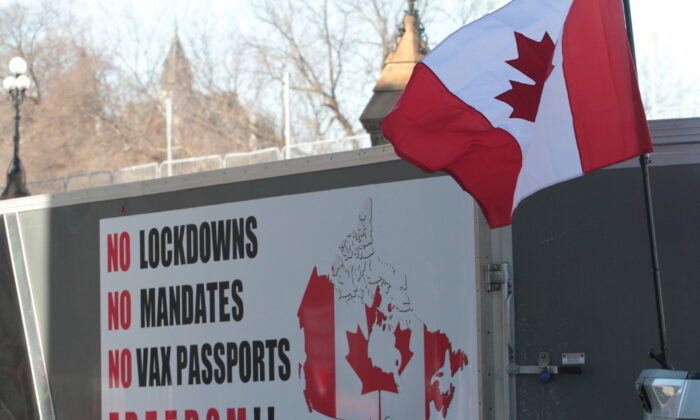 A Canadian flag flutters next to a sign on a truck in the centre of Ottawa on Feb. 12. (Richard Moore/The Epoch Times)
