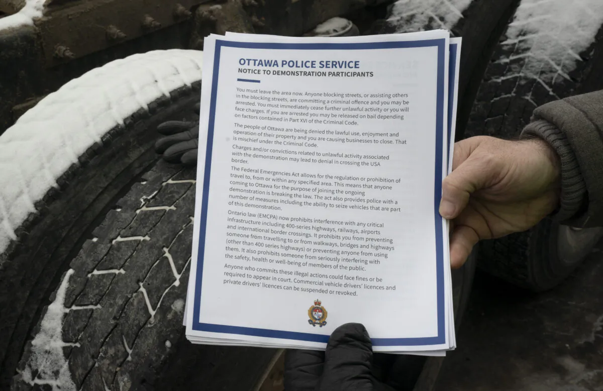 A police officer holds up a notice being distributed to protesters in Ottawa on Feb. 16, 2022. (Adrian Wyld/The Canadian Press)