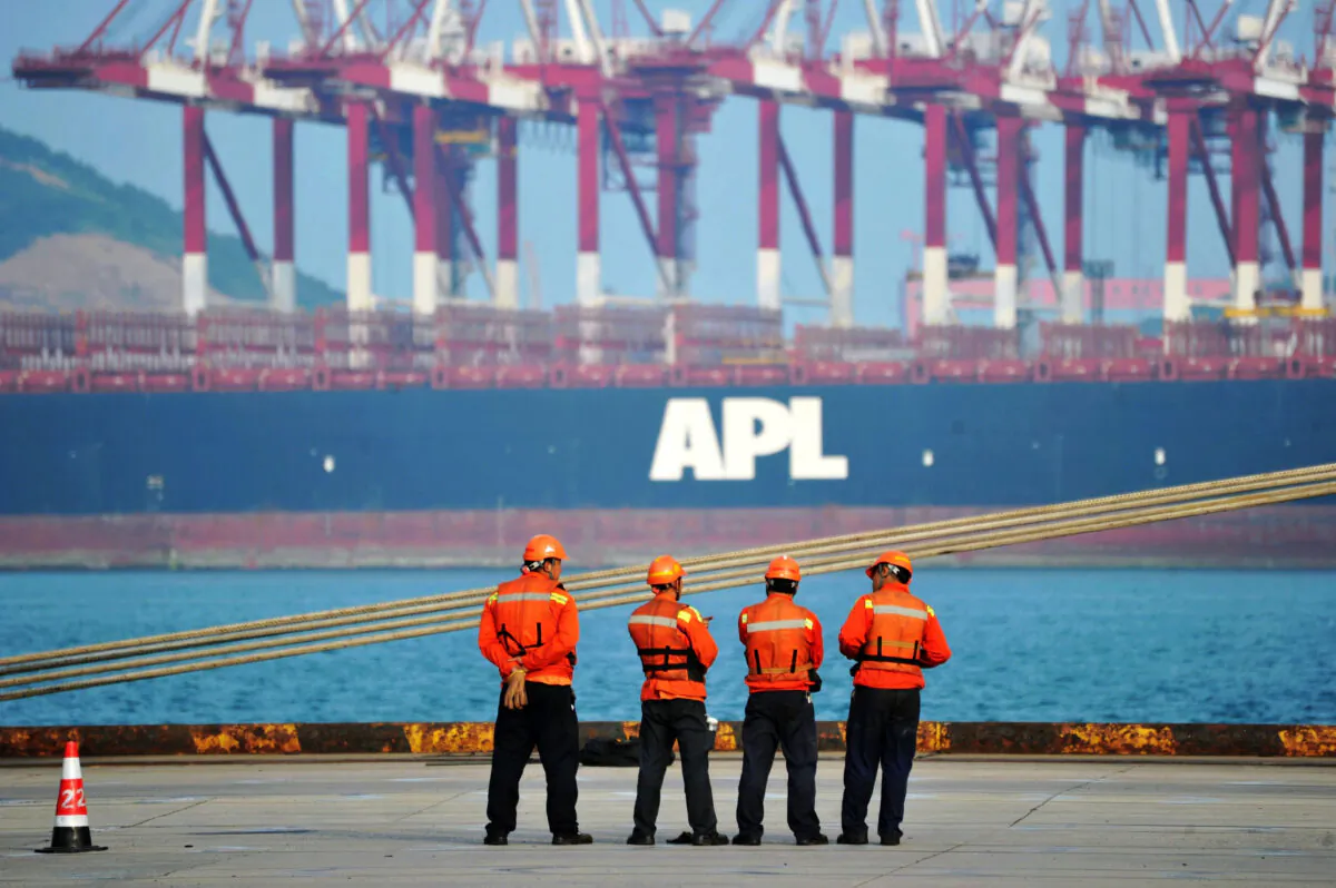 Workers stand near a container ship at the port in Qingdao, a city in eastern China's Shandong Province, on June 8, 2017. (STR/AFP via Getty Images)