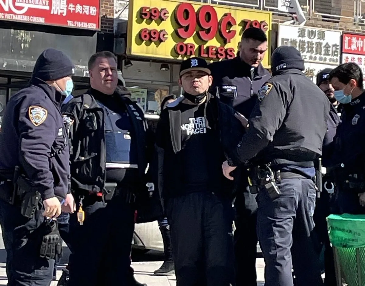 Police arrest Zheng Buqiu for attacking information booths held by Falun Gong practitioners, in Flushing, New York, on Feb. 15, 2022. (Provided by Falun Gong practitioners)