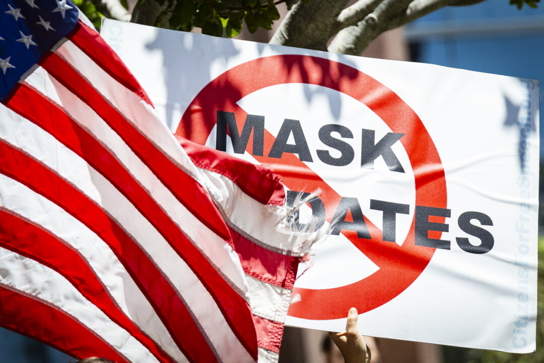 A protestor holds a sign against mask mandates in Costa Mesa, Calif., on June 10, 2021. (John Fredricks/The Epoch Times)