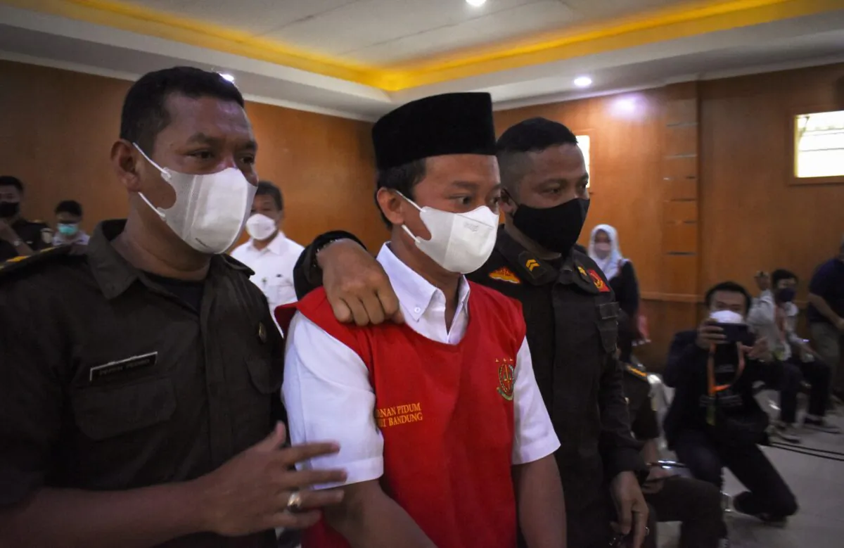 Indonesian teacher Herry Wirawan (C) is escorted prior to his trial at a court in Bandung, West Java on Feb. 15, 2022. (Timur Matahari/AFP via Getty Images)