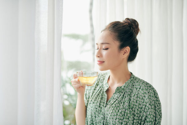 Women,Standing,In,Front,Of,Windows,And,Holding,Tea,Cup