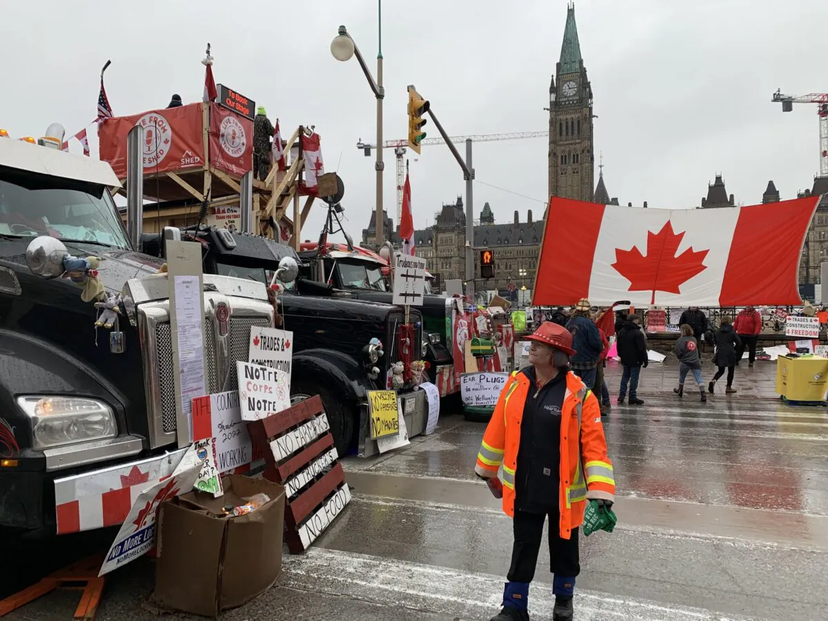 A woman reads the signboards placed by Freedom Convoy protesters near the Parliament Buildings in downtown Ottawa on Feb. 17, 2022 (Jonathan Ren/The Epoch Times)