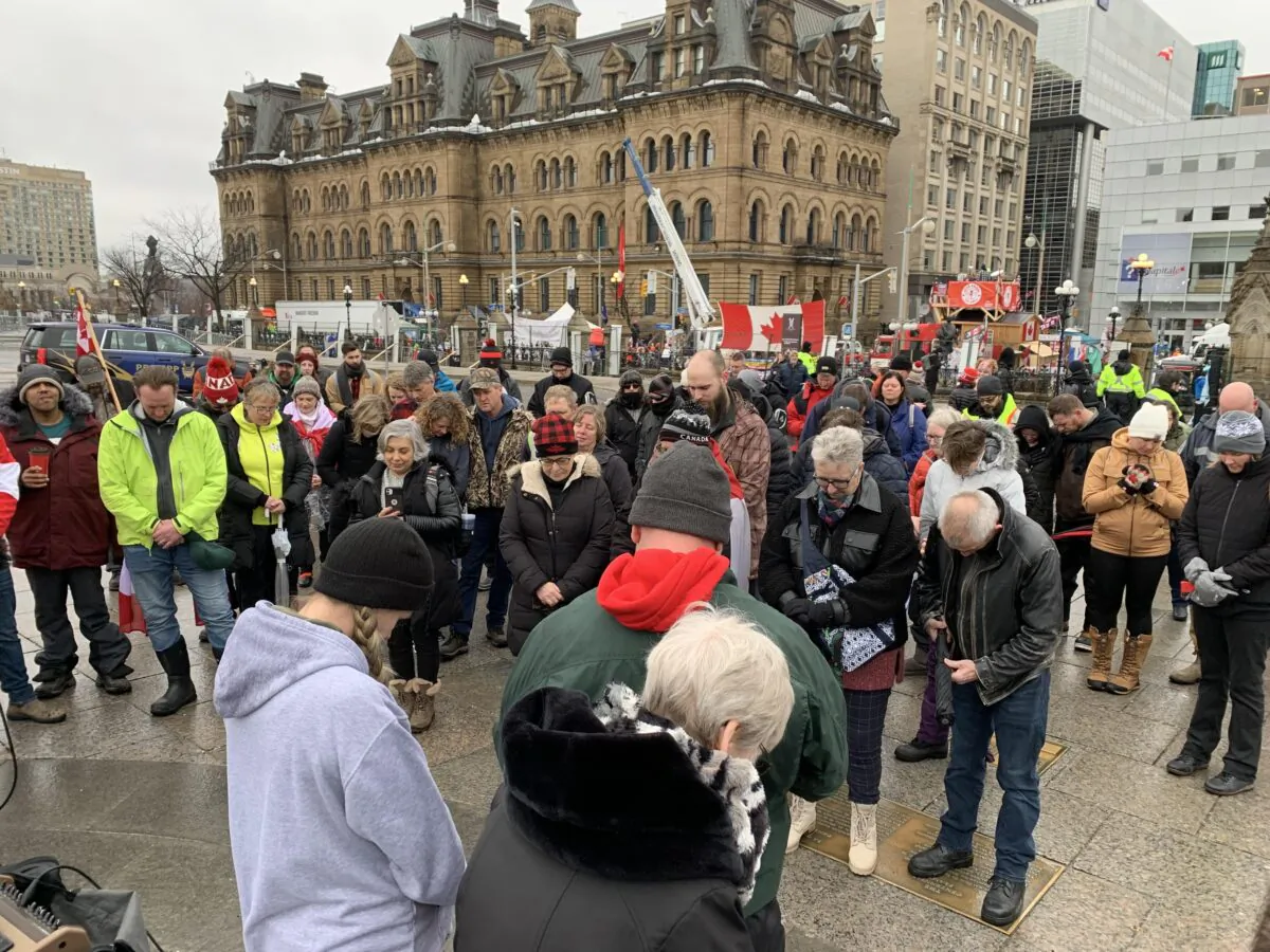 Protesters pray outside Parliament Hill as they gather to demonstrate against COVID-19 mandates and restrictions in Ottawa on Feb. 17, 2022 (Jonathan Ren/The Epoch Times)