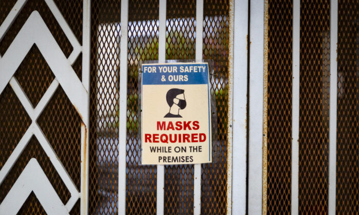 A sign requesting masks hangs on a doorway in Tustin, Calif., on March 10, 2021. (John Fredricks/The Epoch Times)