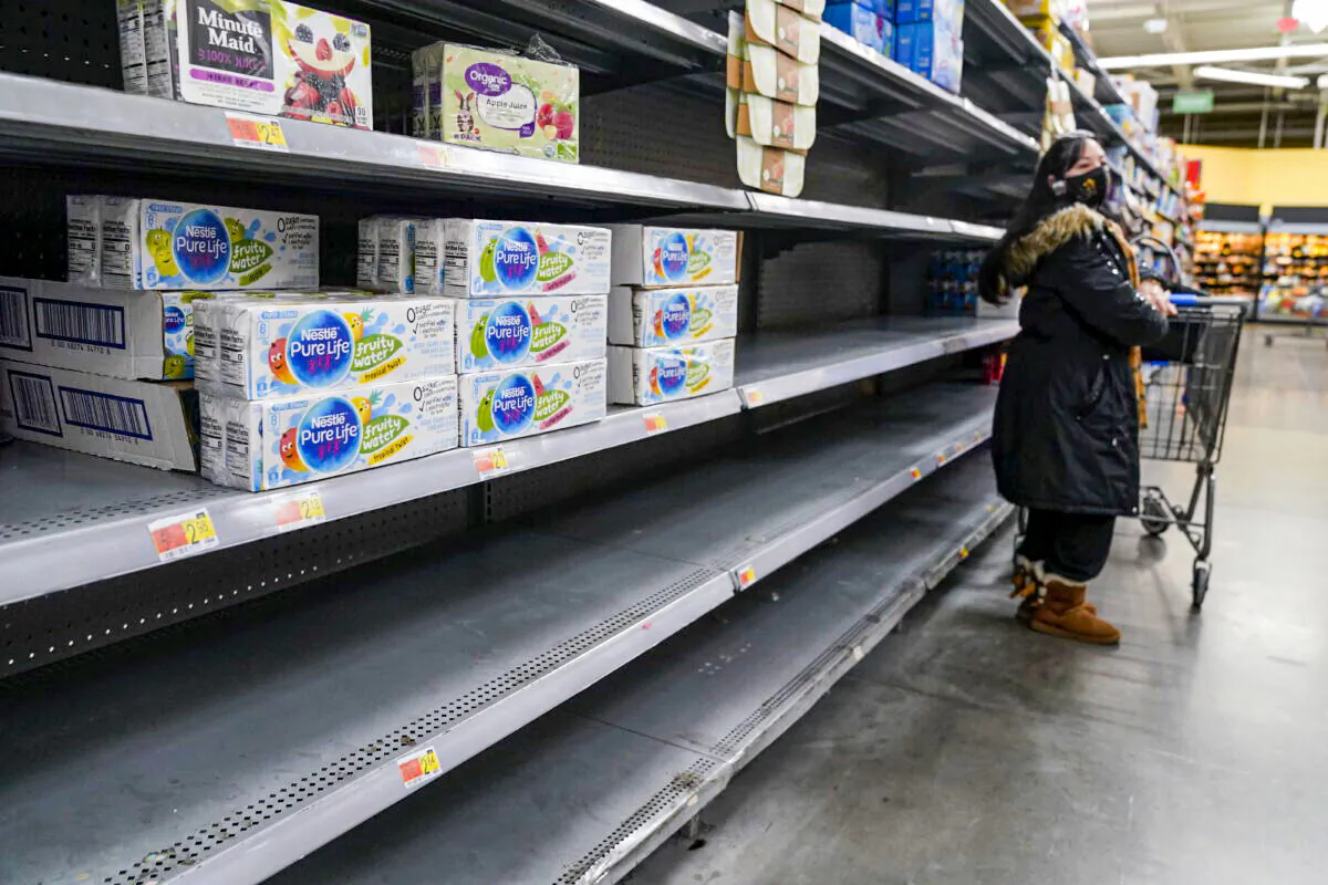 A woman looks over shelves, some of which are empty, at a Walmart store in Teterboro, N.J., on Jan. 12, 2022. The Justice Department is launching a new initiative aimed at identifying companies that exploit supply chain disruptions in the U.S. to make increased profits in violation of federal antitrust laws. (AP Photo/Seth Wenig, File)