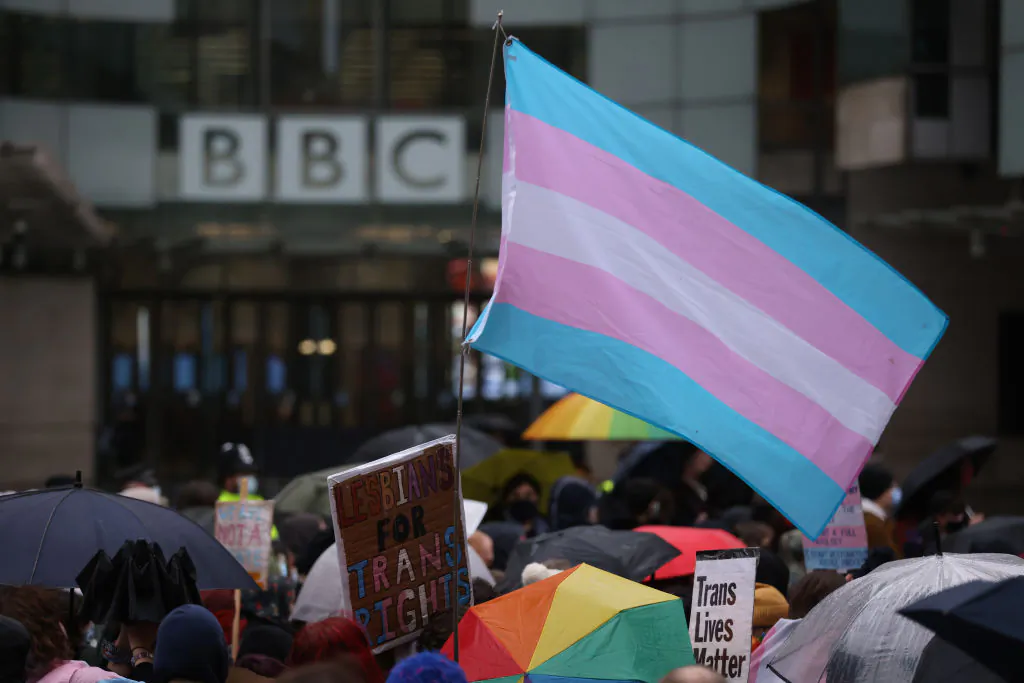 Demonstrators hold placards and wave a transgender pride flag during the Trans Activism UK "British Bigotry Corporation: Platforming Hate Is Not Impartial" protest at BBC Broadcasting House in London, on Jan. 8, 2022. (Hollie Adams /Getty Images)