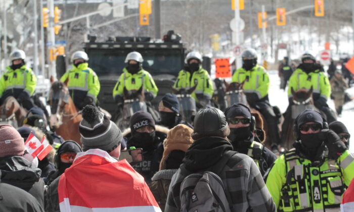 Protesters confront a police line backed up by mounted officers in Ottawa on Feb. 18, 2022. (Richard Moore/The Epoch Times)
