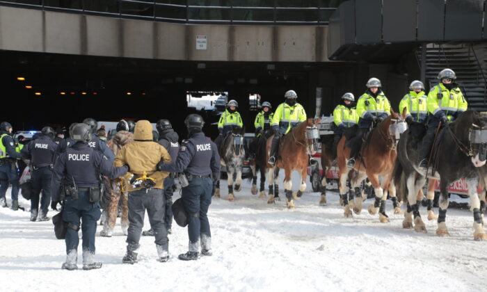 Police arrest protestors as mounted officers move towards the main Freedom Convoy protest in downtown Ottawa on Feb. 18, 2022. (Richard Moore/The Epoch Times)