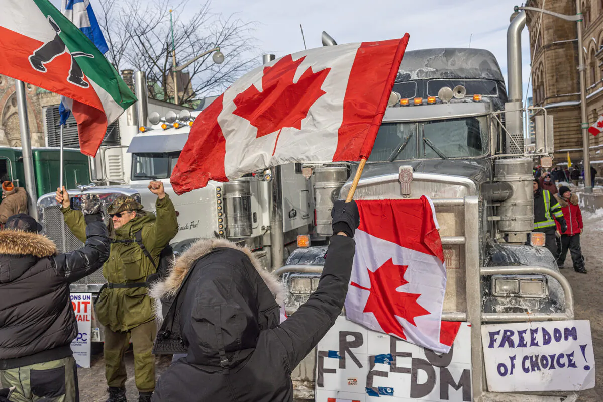 A woman waves a flag and cheers on truckers in protest of COVID-19 vaccine mandates in Ottawa, Canada, on Jan. 30, 2022. (Alex Kent/Getty Images)