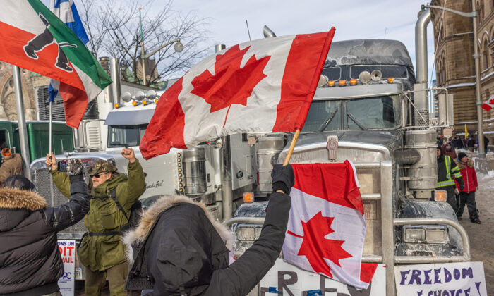 A woman waves a flag and cheers on truckers in protest of COVID-19 vaccine mandates in Ottawa, Canada, on Jan. 30, 2022. (Alex Kent/Getty Images)