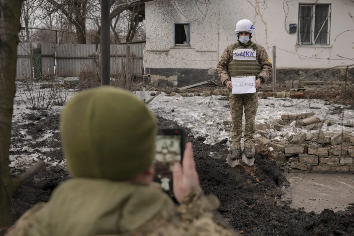 Members of the Joint Centre for Control and Coordination on ceasefire of the demarcation line, or JCCC, take forensic photos of damage to a house from artillery shell that landed in Vrubivka, Ukraine, on Feb. 17, 2022. (AP Photo/Vadim Ghirda