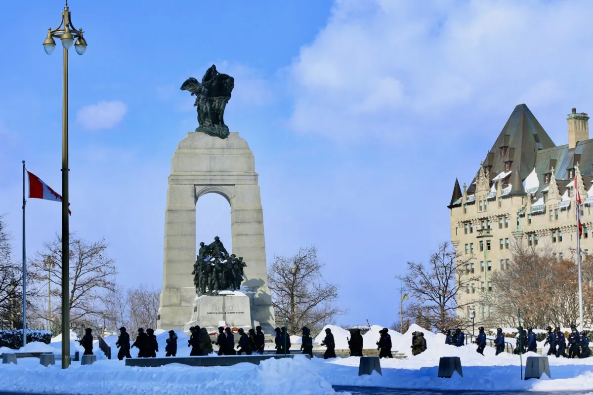 Police walk by the National War Memorial in Ottawa as operations to clear protesters continue on Feb. 19, 2022. (Jonathan Ren/The Epoch Times)