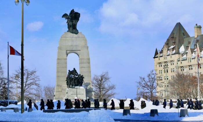 Police walk by the National War Memorial in Ottawa as operations to clear protesters continue on Feb. 19, 2022. (Jonathan Ren/The Epoch Times)