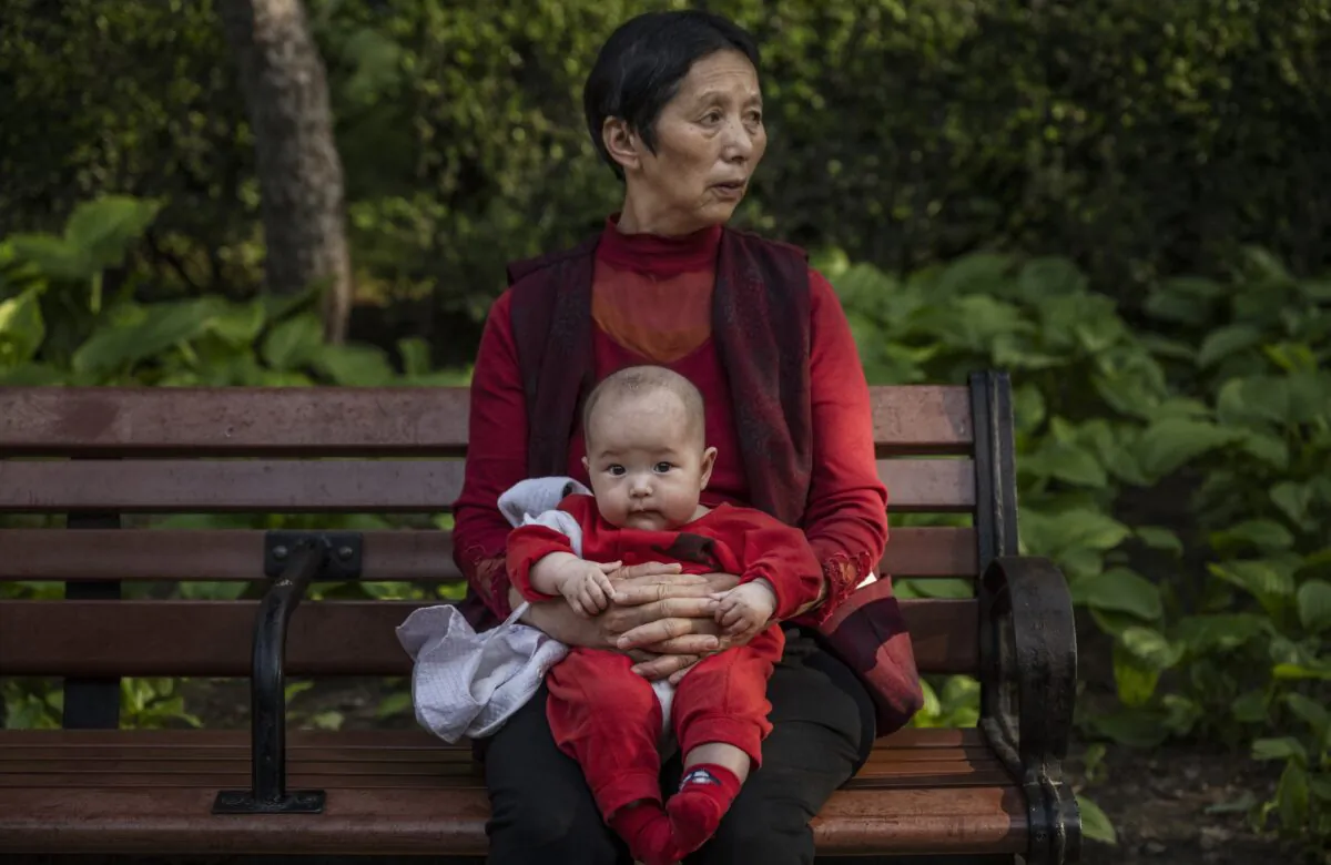 A woman holds a baby at a park in Beijing, China, on May 12, 2021. (Kevin Frayer/Getty Images)