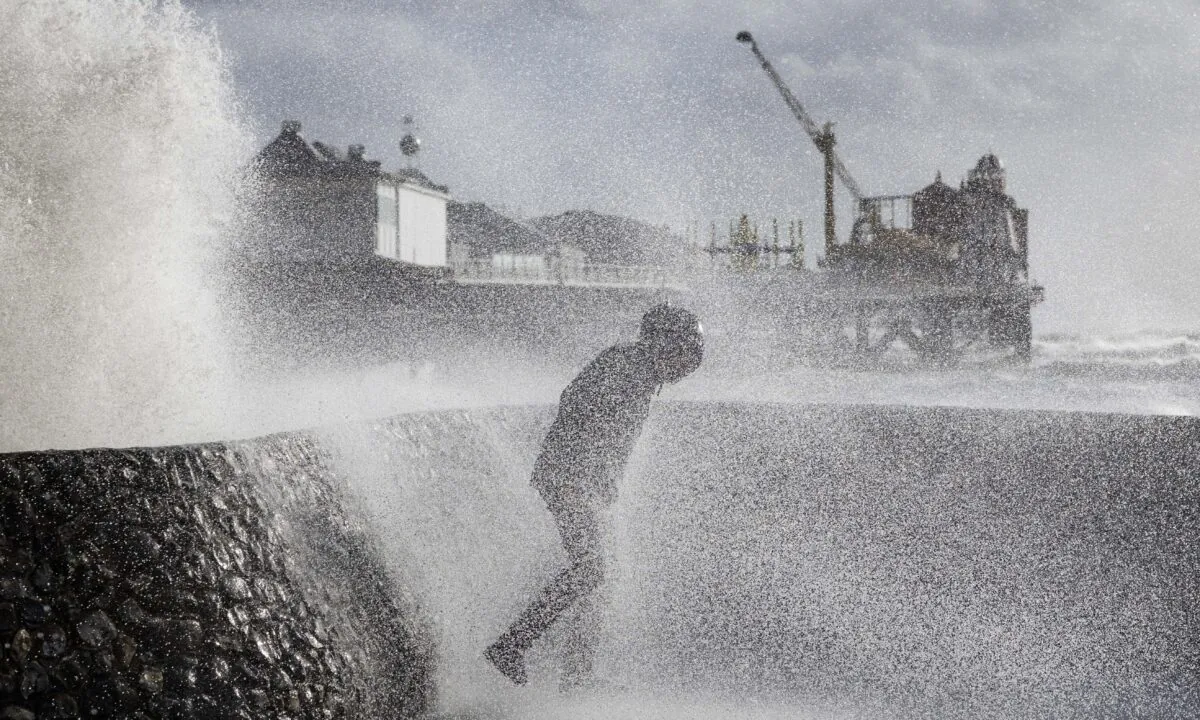 A young man braves the elements as Storm Eunice causes large waves to crash against the seawall alongside Brighton Pier in Brighton, England, on Feb. 18, 2022. (Dan Kitwood/Getty Images)