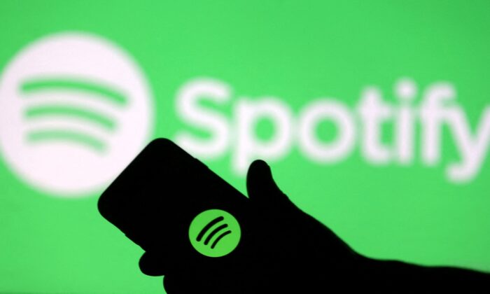 A smartphone is seen in front of a screen projection of Spotify logo, in this picture illustration taken on April 1, 2018. (Dado Ruvic/Illustration/Reuters)