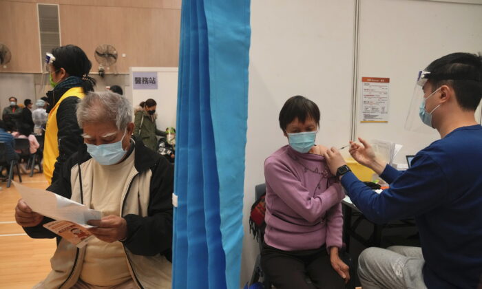 A woman (R) receives a dose of China's Sinovac COVID-19 coronavirus vaccine at a community vaccination center in Hong Kong, Friday, Feb. 25, 2022. (AP Photo/Kin Cheung)