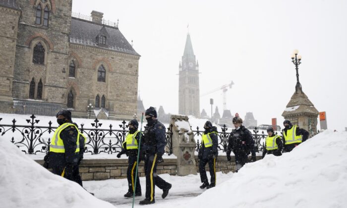 Police officers walk pass the Parliament buildings in Ottawa on Feb. 20, 2022. (The Canadian Press/Adrian Wyld)